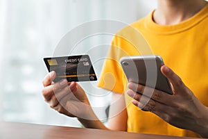 Woman hand holding credit card and using smartphone for paying products online via the Internet