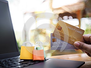 Woman hand holding credit cards and shopping bags on a laptop keyboard. Concepts about online shopping that offers home delivery