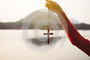 Woman hand holding cross crucifixion of the jesus christ at nature blackground