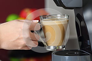 Woman hand holding a cup in a coffee maker