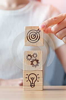 Woman hand holding dartboard above Gear and Lightbulb icon block. business planning process, goal, strategy, target, mission,