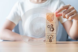 Woman hand holding dartboard above Gear and Lightbulb icon block. business planning process, goal, strategy, target, mission,