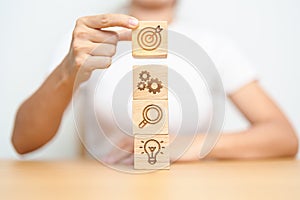 Woman hand holding dartboard above Gear, magnifying and Lightbulb icon block. business planning process, goal, strategy, target,