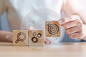 Woman hand holding dartboard, Gear and Lightbulb icon block on table. business planning process, goal, strategy, target, mission,