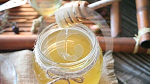 Woman hand holding dipper and dip in jar of honey