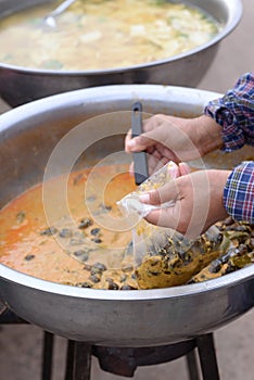 Woman hand holding dipper scooping freshwater snail in red curry Put in a plastic bag