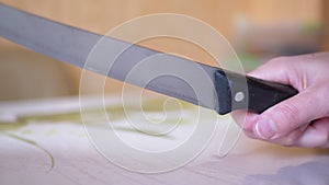 A Woman Hand is Holding a Dirty, Sharp, Long Kitchen Knife over Surface of Table