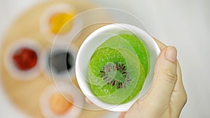 Woman hand holding dried kiwi fruits in the white bowl, Close-up, Top view