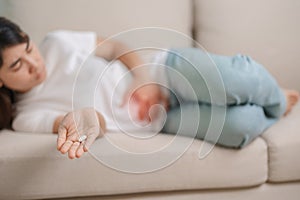 woman hand holding and eating medicine painkiller pill on the sofa at home, for stomach ache, Diarrhea Pain from food poisoning,