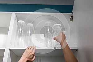 Woman hand holding empty plastic container with lid on shelf of