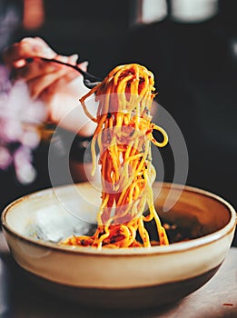 Woman hand holding fork and knife with spaghetti bolognese in bowl
