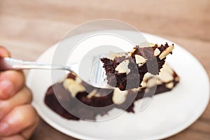 Woman hand holding fork picking sliced homemade brownies.
