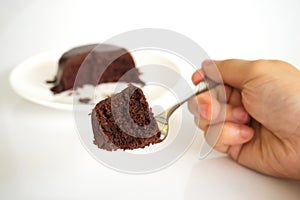 Woman hand holding fork served chocolate cake with chocolate fud