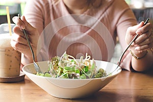 Woman hand holding fork and spoon to eating vegetable salad with