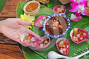 Woman Hand Holding a Fresh Lotus Petal Savory Wrapped Called Miang kham in Thai Language