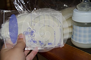 Woman hand holding frozen breast milk in storage bags and baby bottle with fresh expresed breastmilk