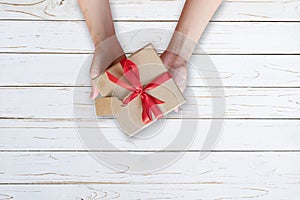 Woman hand holding gift box on wood plank and painted in white color with copy space