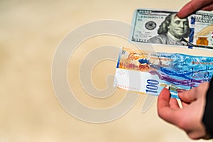 Woman hand holding and giving money. World money concept, close up of 100 swiss franc banknote and 100 US dollar, photo of CHF and