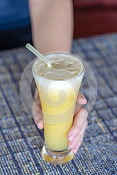 Woman hand holding a glass of fresh pineapple juice, close up