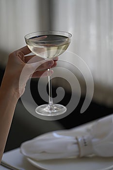 Woman hand holding glass with martini cocktail, close-up