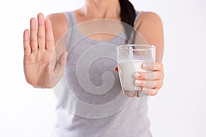 Woman hand holding glass of milk having bad stomach ache because of Lactose intolerance and another hand shows stop sign.