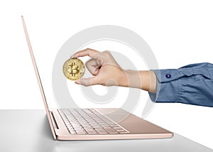 Woman hand holding golden bitcoin in front of a laptop