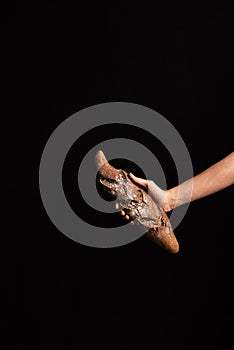 A woman hand holding a handmade rye bread from one side on a black background