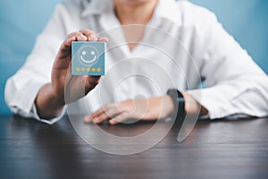 Woman hand holding happy face smile face icon on cube blue object. Customer experience and service with satisfaction concept.