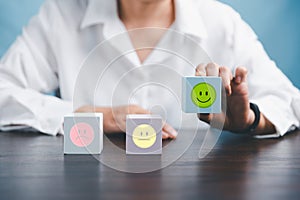 Woman hand holding happy face smile face icon on cube blue object. Customer experience and service with satisfaction concept.