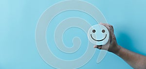 Woman hand holding happy face smile face icon on round blue object. Customer experience and service with satisfaction concept.