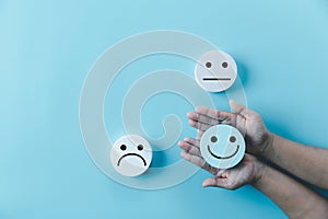 Woman hand holding happy face smile face icon on round blue object. Customer experience and service with satisfaction concept.