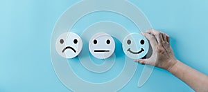 Woman hand holding happy face smile face icon on round blue object. Customer experience and service with satisfaction concept.