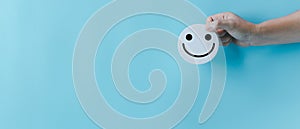 Woman hand holding happy face smile face icon on round blue object. Customer experience and service with satisfaction concept.