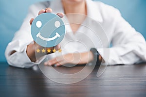Woman hand holding happy face smile face icon on round blue object. Customer experience and service with satisfaction concept.