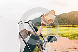 Woman hand holding hat on the car relaxing and happy traveler with mountain background