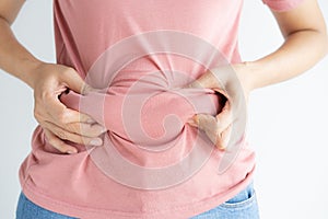 Woman hand holding her own belly fat and cellulite on white background. Women before weight loss and shape up healthy stomach