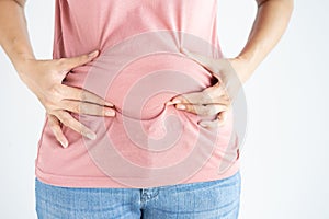 Woman hand holding her own belly fat and cellulite white background. Women before weight loss and shape up healthy stomach