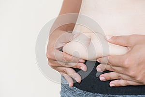Woman hand holding her own belly fat.