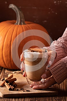 Woman hand holding homemade pumpkin spice latte made from scratch