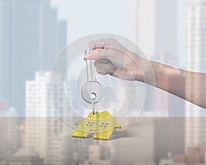 Woman hand holding key with house shape keyring