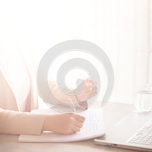 Woman hand holding light bulb, notebook, laptop, pen, documents on cream background with copy space. Creative idea, new