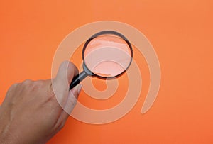 Woman hand holding  Magnifying glass  isolate on a orange backgroun