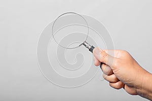 woman hand holding magnifying glass isolated on gray background. optical zoom lens is macro tool, concept for education, science