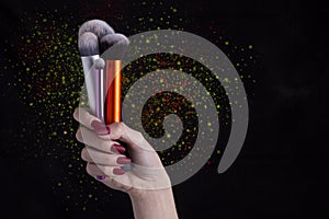 Woman hand holding Make-up brushes with powder explosion photo