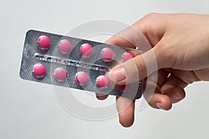 Woman Hand holding medical drugs - full silver leaflet of red pills in common tablets shape