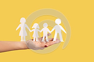 Woman hand holding paper family chain, relationships between children and parents.