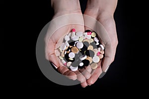 Woman hand holding pill on black background