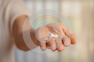 Woman hand holding pills on blurred background