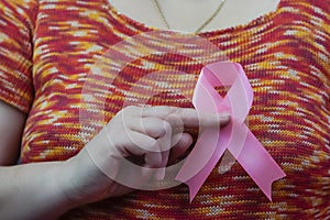 Woman hand holding pink breast cancer awareness ribbon.