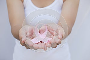 Woman hand holding pink breast cancer awareness ribbon.